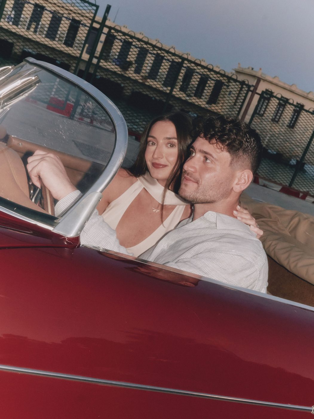The couple together in a red vintage Porsche